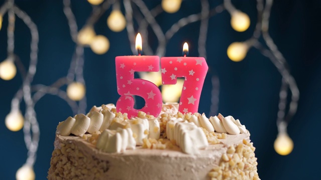 生日蛋糕与57号粉红蜡烛在蓝色的背景。蜡烛吹灭。慢动作和近景视频素材