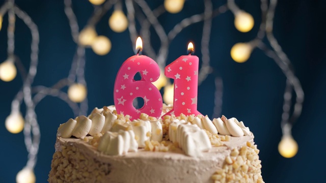 生日蛋糕与61号粉红蜡烛在蓝色的背景。蜡烛吹灭。慢动作和近景视频素材