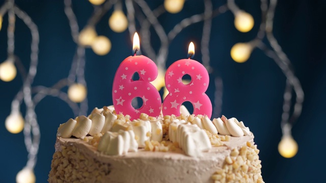 蓝色背景上的68号粉红蜡烛生日蛋糕。蜡烛吹灭。慢动作和近景视频素材
