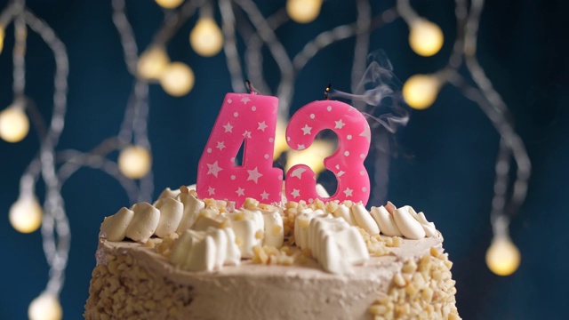 蓝底43号粉红蜡烛生日蛋糕。蜡烛吹灭。慢动作和近景视频下载