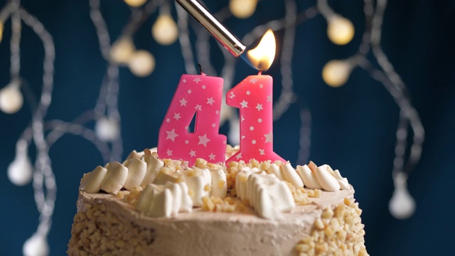生日蛋糕与41号粉红蜡烛在蓝色的背景。蜡烛被点燃了。慢动作和近景视频素材