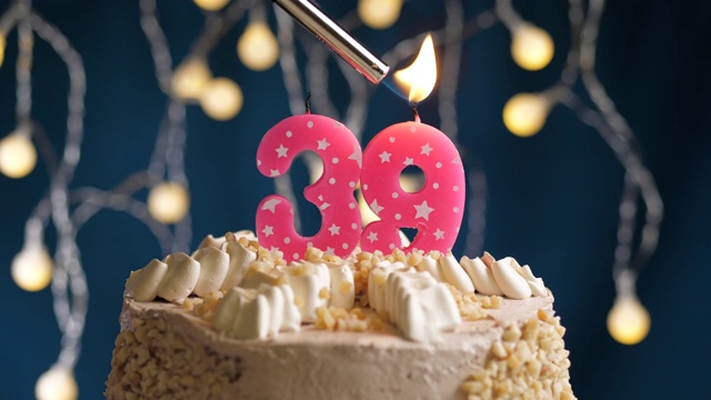 生日蛋糕与39号粉红蜡烛在蓝色背景。蜡烛被点燃了。慢动作和近景视频下载