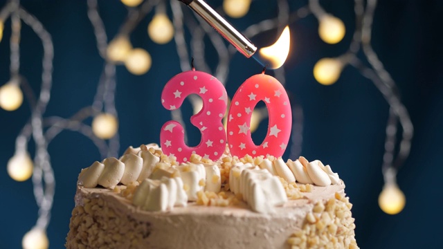 生日蛋糕与30号粉红蜡烛在蓝色的背景。蜡烛被点燃了。慢动作和近景视频下载