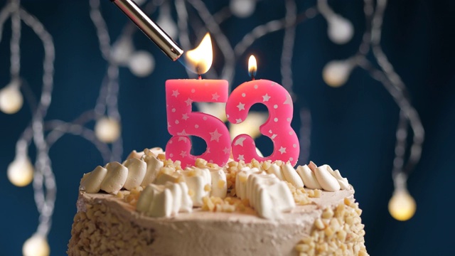 生日蛋糕与53号粉红蜡烛在蓝色的背景。蜡烛被点燃了。慢动作和近景视频素材