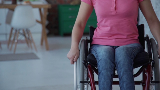 坐在轮椅上的成年妇女在家里向前走视频素材