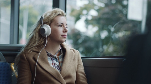 一个女人在公交车上戴着耳机听音乐视频素材
