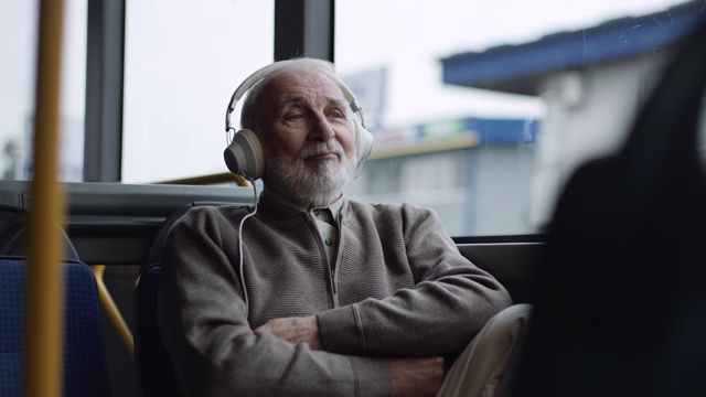 一位老人在公交车上戴着耳机听音乐视频素材