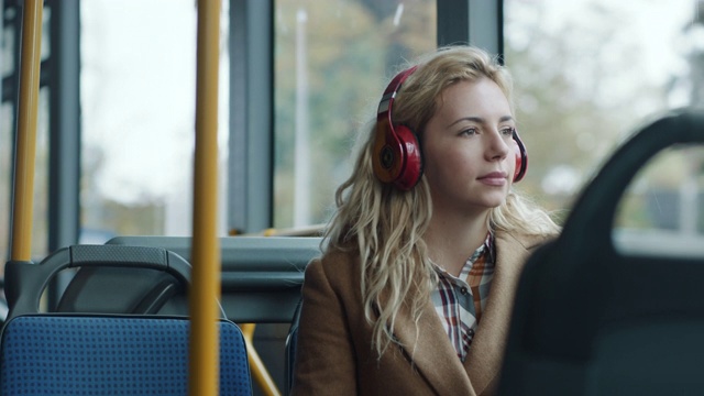 一个女人在公交车上戴着耳机听音乐视频素材