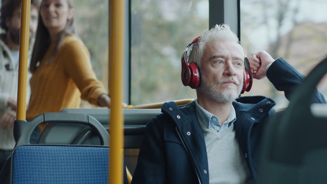 一个在公交车上戴着耳机听音乐的成熟男人视频素材