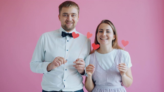 在粉红色的背景上，快乐的人们抱着相爱和幸福的心视频下载
