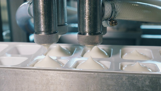 工厂里的自动化机器把乳制品倒进容器里。视频下载