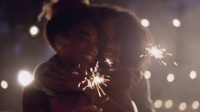 美丽的非裔美国人夫妇手持烟花跳舞，拥抱和亲吻视频下载