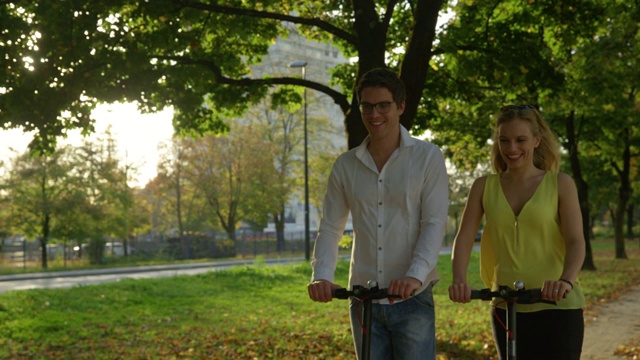 特写:微笑的白人夫妇骑着电动摩托车沿着风景优美的大街视频素材