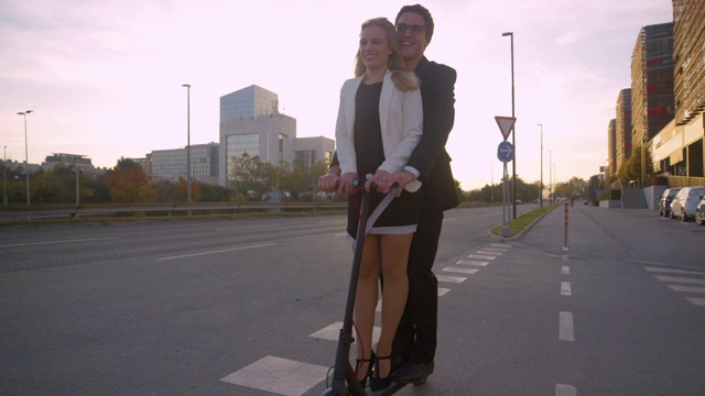 特写:快乐的男人和女朋友骑着电动滑板车从金融区通勤。视频下载