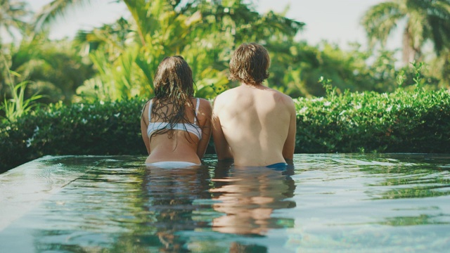 迷人的夫妇享受热带游泳池视频素材
