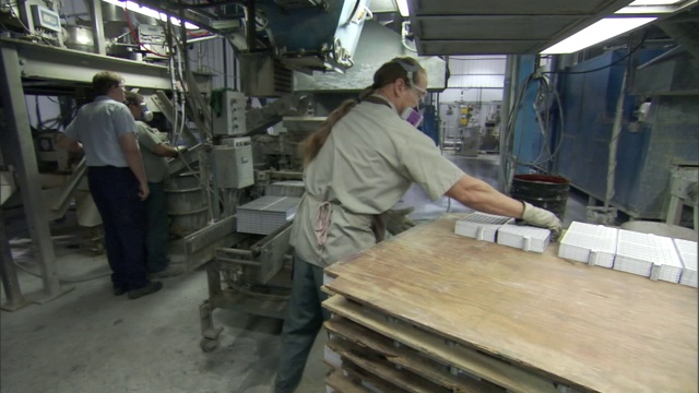 一名生产工人将成堆的金属板放在传送带上。视频素材