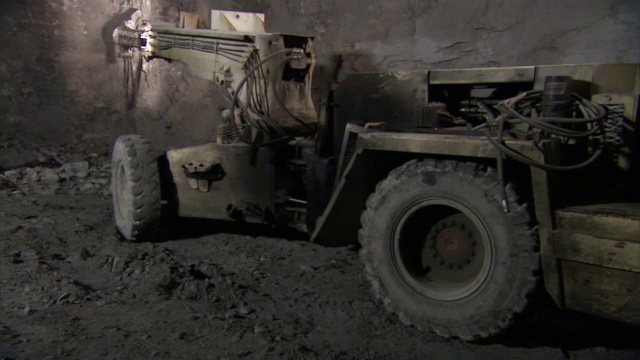 一台配备凿子的挖掘机在矿井壁上挖掘。视频素材