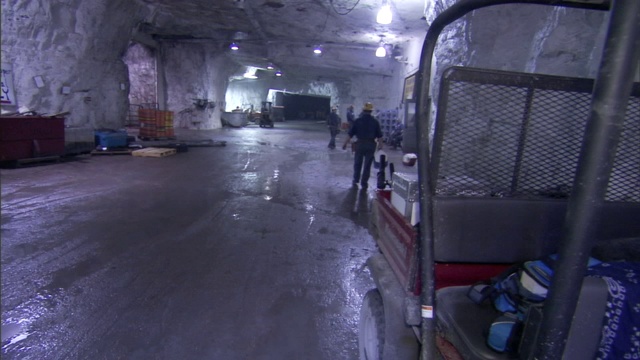 一个戴安全帽的矿工走过走廊。视频下载