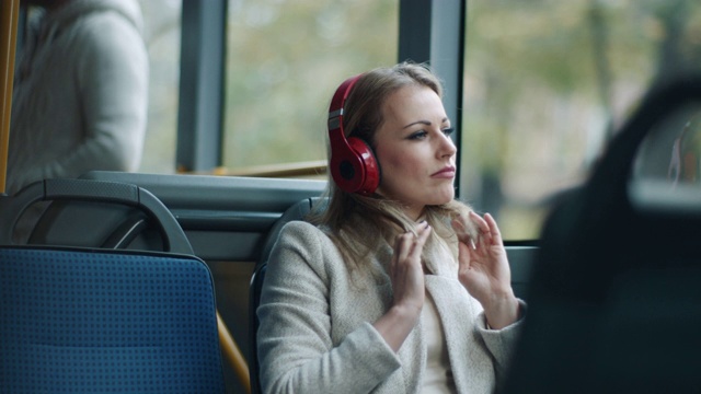 一个女人在公共汽车上戴着耳机听音乐视频素材