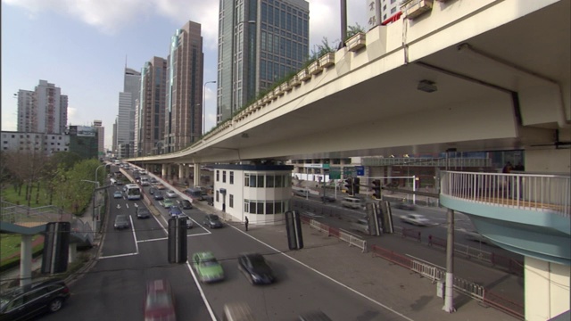 在繁忙的城市街道上，交通从立交桥下移动。视频下载