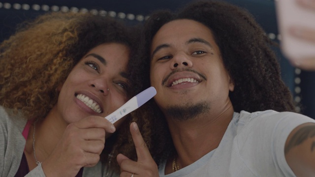 CU的一个非洲裔美国夫妇与他们的阳性怀孕测试微笑自拍视频素材