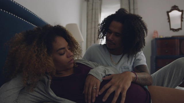 一名非裔美国男子揉着他疲惫不堪的女友怀孕的肚子视频素材
