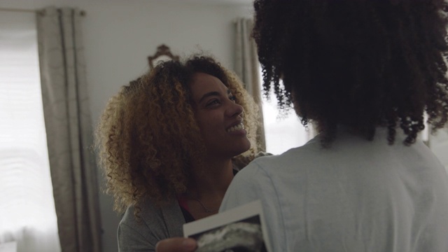 一名非裔美国妇女拿着超声波照片拥抱她的男友视频下载