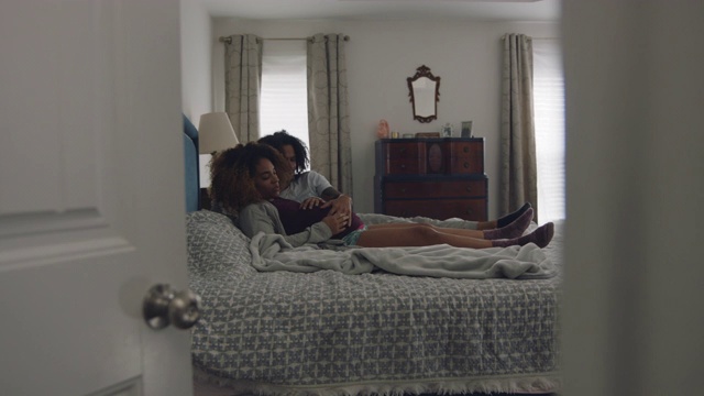 一名非裔美国人躺在床上，把耳朵贴在他怀孕的妻子的肚子上视频素材