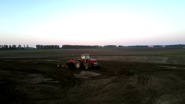 农田上方的红色拖拉机用犁耕地视频下载