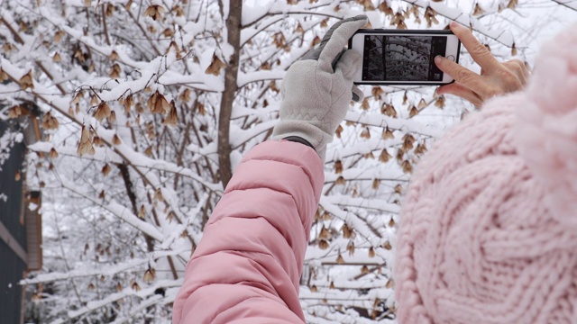 一名女子在雪地里用智能手机拍照片视频下载