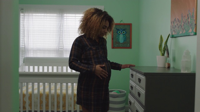 一位即将出生的多民族妇女从婴儿保育室的梳妆台里拿出一块尿布视频素材