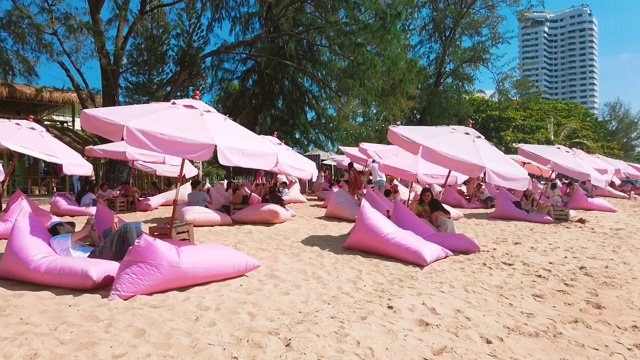 泰国春武里芭堤雅，游客在著名的涂涂海滩上放松，海滩上装饰着粉红色的雨伞。视频下载