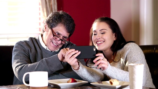 西班牙裔老人和女儿在看智能手机视频素材