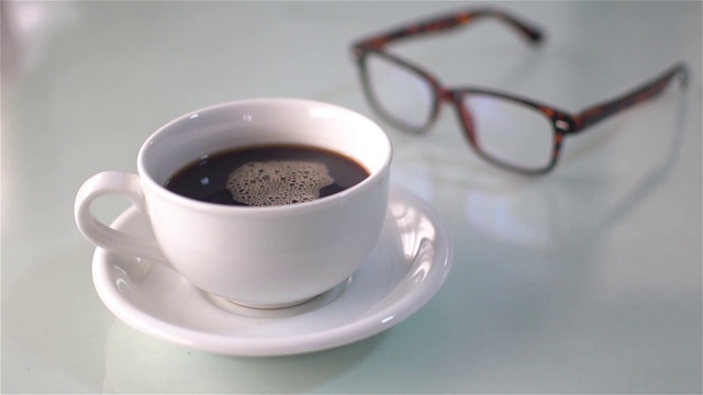 在白色的桌子上倒咖啡和杯子，慢镜头视频素材