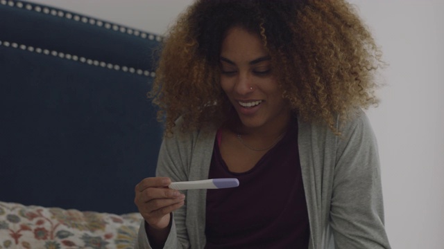 一个年轻的女人看到验孕结果呈阳性，就打电话给她的男朋友庆祝视频素材