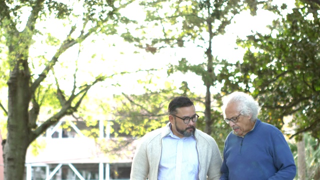 西班牙裔老人边走边和成年的儿子说话视频素材