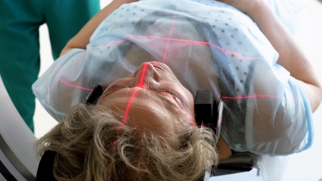 近距离拍摄的女性成熟的病人躺在一台CT扫描仪的桌子上。电脑断层扫描仪对老年妇女的身体和大脑进行扫描。医疗诊所的高科技设备。4 k视频素材