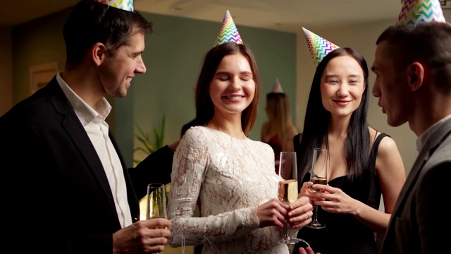 一个年轻人带着女朋友来参加聚会，并把她介绍给几个朋友。年轻人戴着派对帽，一边喝着香槟，一边互相问候视频下载
