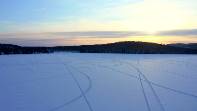 一个湖与雪地上的雪车痕迹的4K空中视频在日落，魁北克，加拿大视频下载