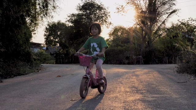 小女孩在乡村的路上骑自行车。视频素材