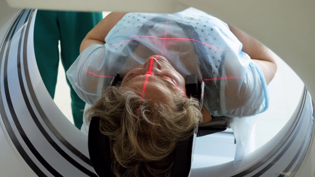 近距离拍摄的女性成熟的病人躺在一台CT扫描仪的桌子上。电脑断层扫描年长妇女的大脑。医疗诊所的高科技设备。4 k视频素材