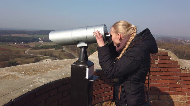 迷人的女性游客使用塔光学查看周围山谷附近的旧城堡视频下载