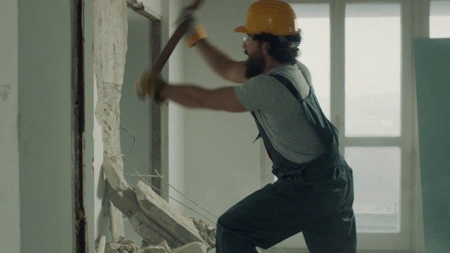 建筑工人正在用大锤拆除墙壁视频素材