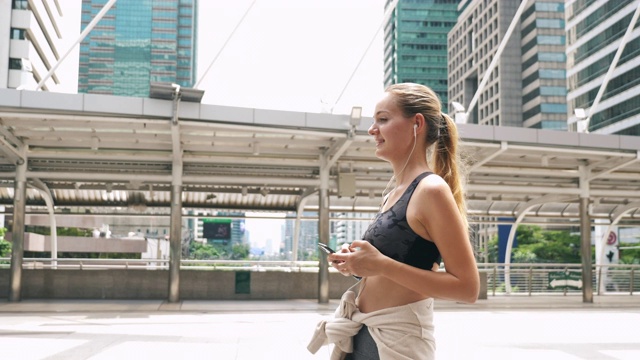 运动女性在城市锻炼后使用智能手机视频素材