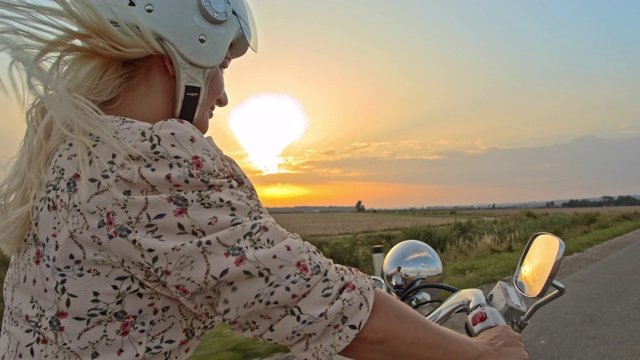 日落时分，在乡村公路上骑摩托车的女人视频素材