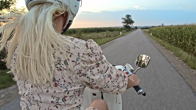 SLO MO中年成年女子骑着摩托车在日落的乡村道路视频素材