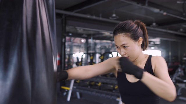 女子跆拳道练习用沙袋拳击手在健身馆练习拳击健康的生活方式，竞技体育女子训练耐力强的锻炼。4K超高清影片，弧度拍摄视频素材