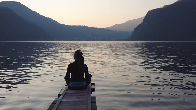 女人在瑜伽姿势在码头的尽头在湖上冥想视频素材