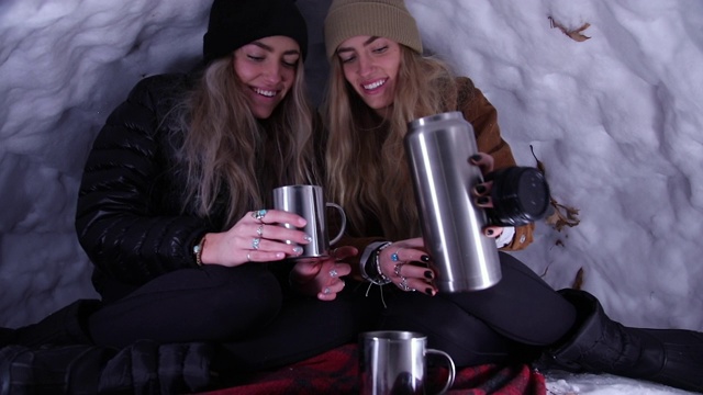 年轻的女人坐在冰屋往杯子里倒热饮视频下载