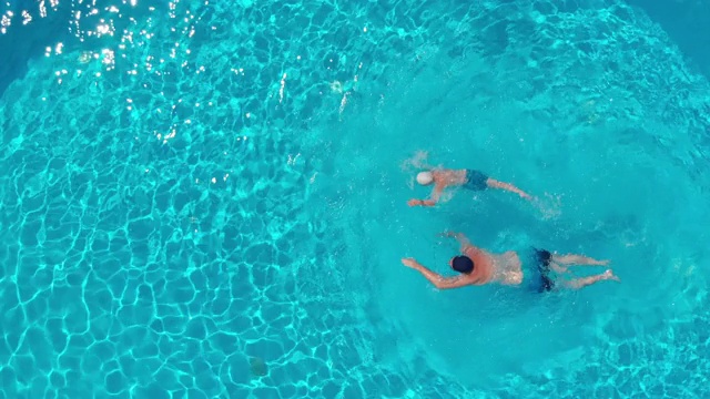 一个男人和一个男孩在一个透明的游泳池游泳的俯视图视频下载